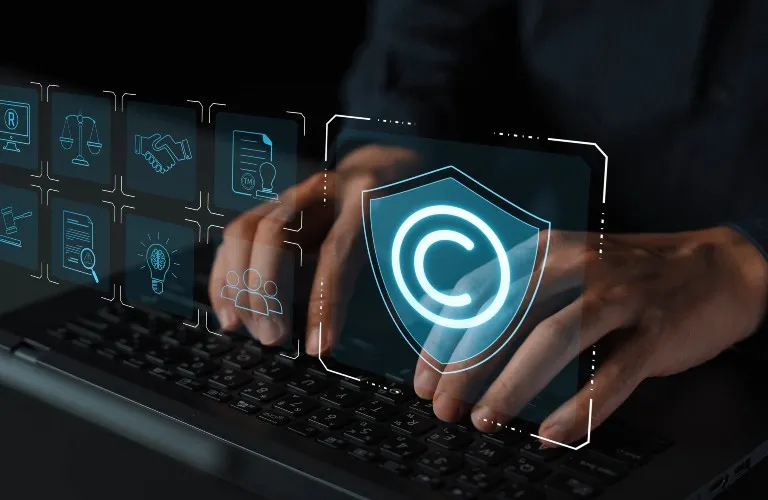Person typing on a laptop keyboard with digital copyright and legal icons overlayed.