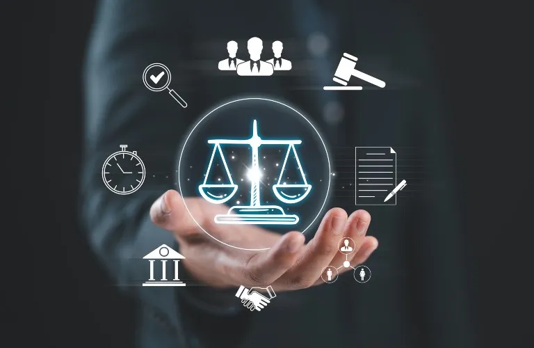 Hand holding digital scales of justice icon surrounded by legal and business symbols on dark background.